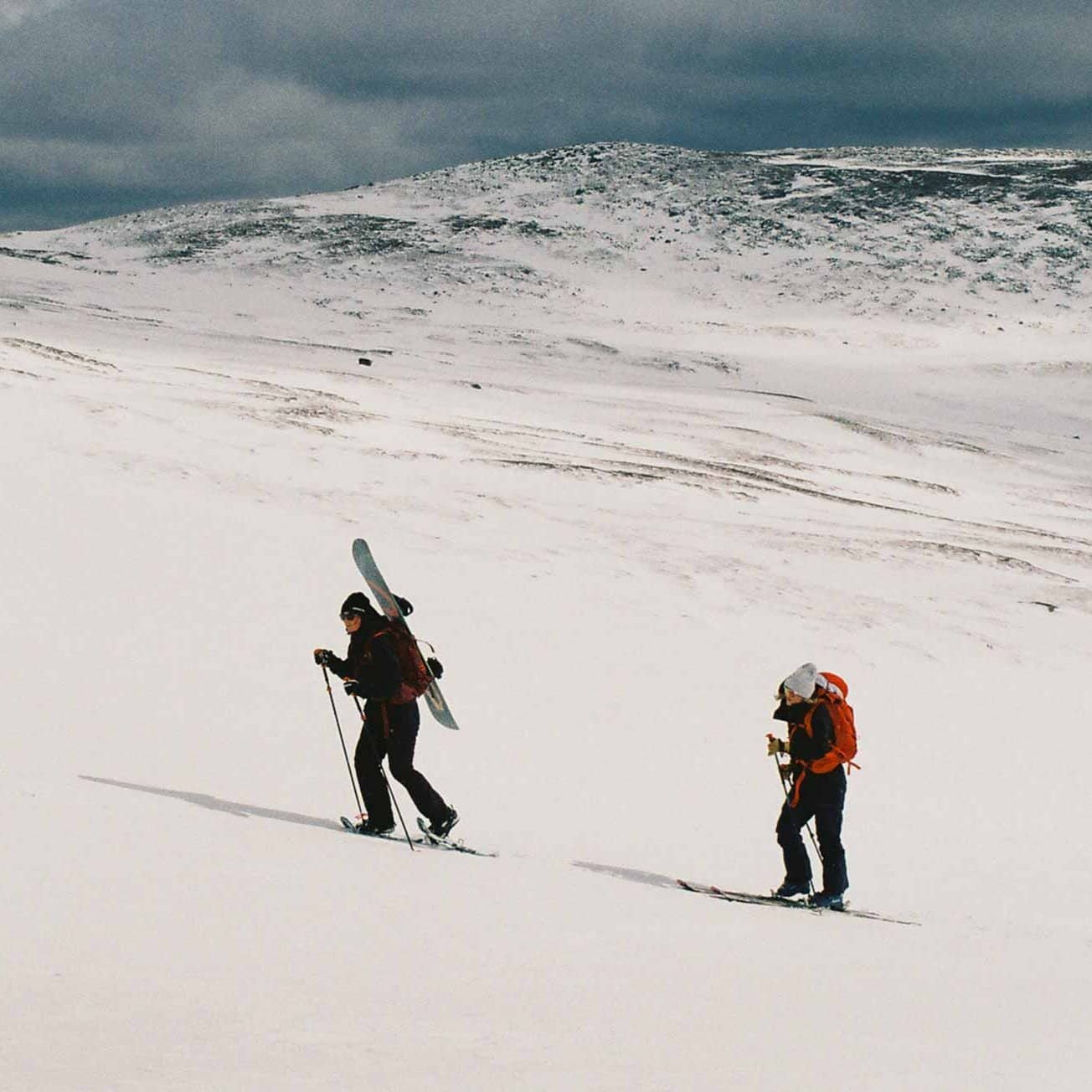 Två personer går på randonee-skidor uppför fjället.